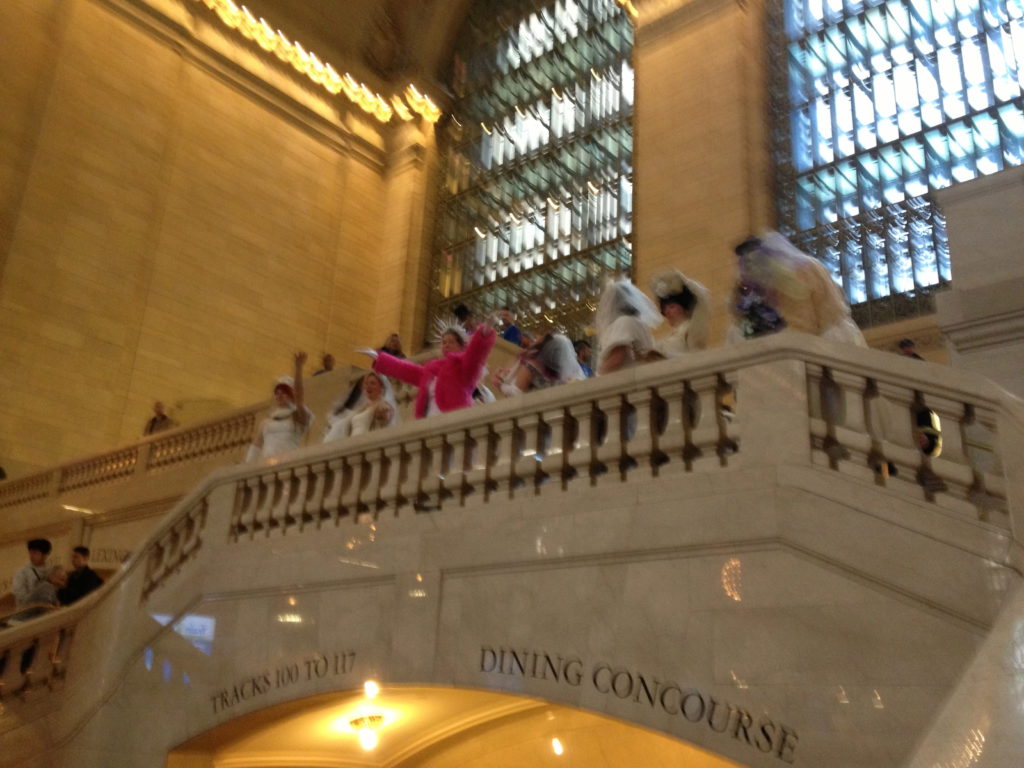 a line of brides on a balcony at Grand Central Station