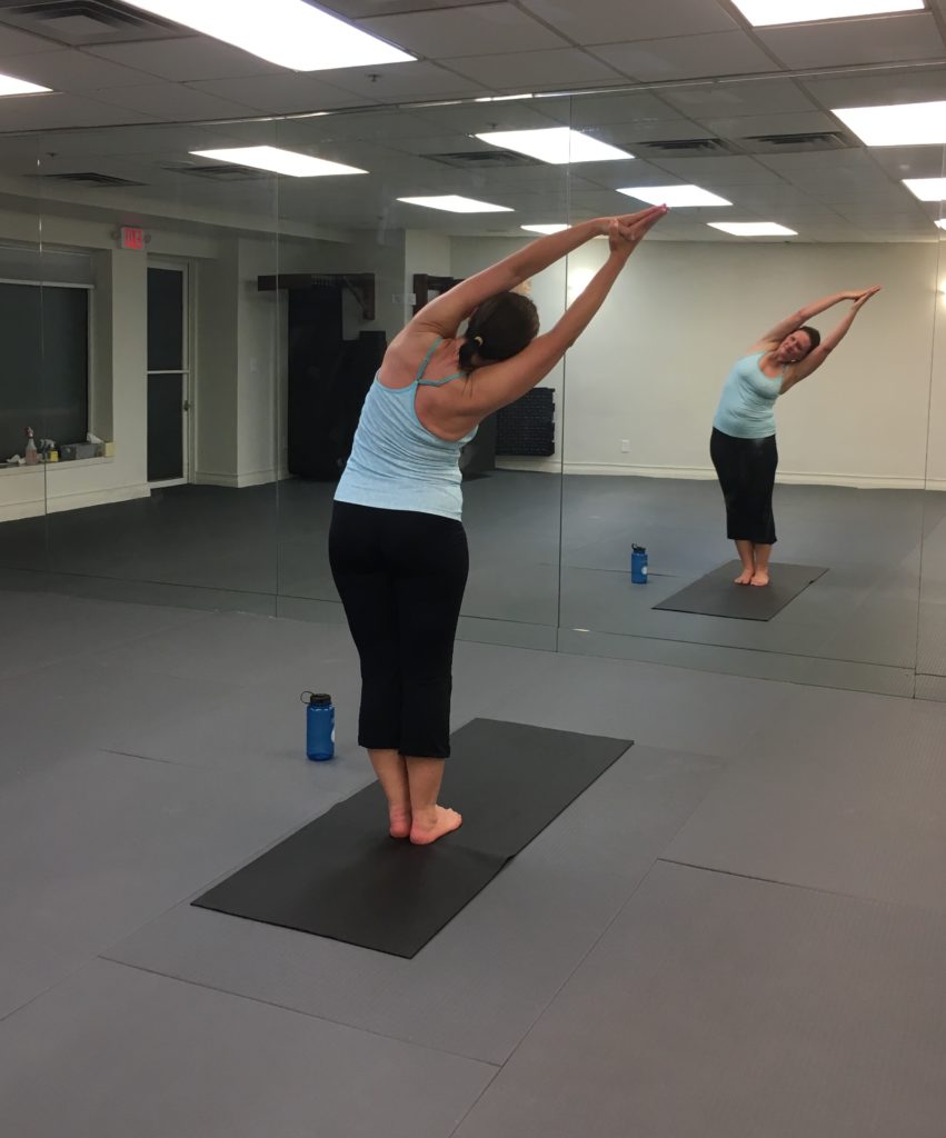 Stacey doing half moon pose in mirrored hot yoga room