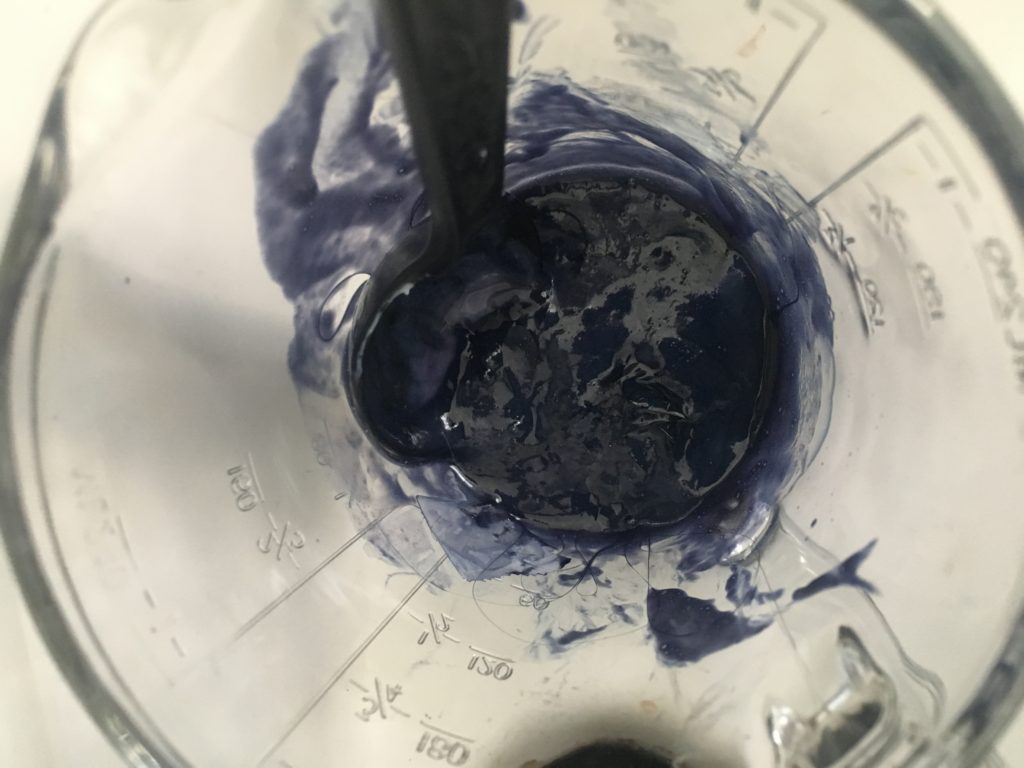 glass measuring cup with blue hair dye