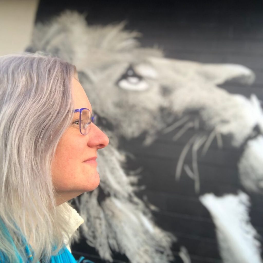 me with grey pride hair in front of bw mural of lion