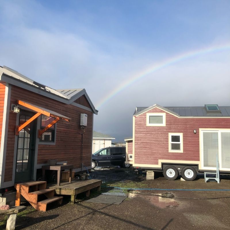 two tiny houses with rainbow overhead
