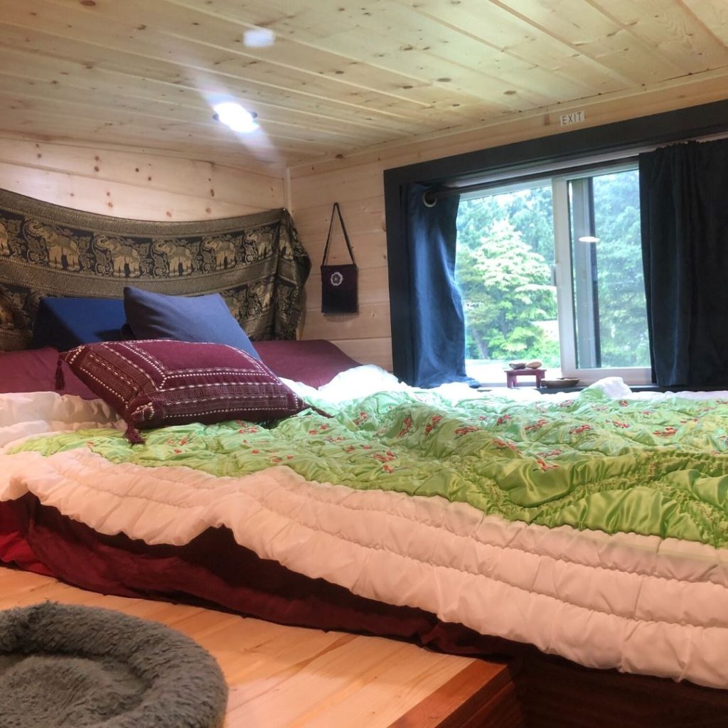 bedroom loft with green & white blanket inside tiny house