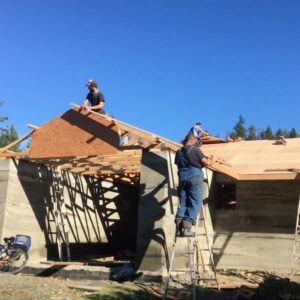 Dave's friends working on the wood roof of his rammed earth home