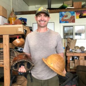 Dan Coyle holding wood helmets in his workshop