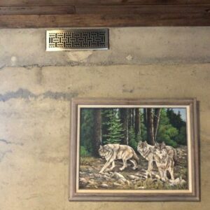 rammed earth wall with heat register and a painting of wolves