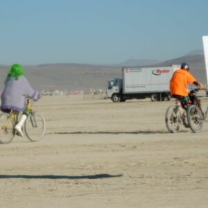 Playa Will Provide illustrated by woman with green hair and man in orange shirt riding bikes at Burning Man 2014